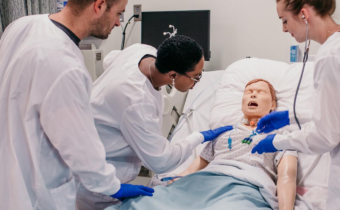 Three students working with patient manikin